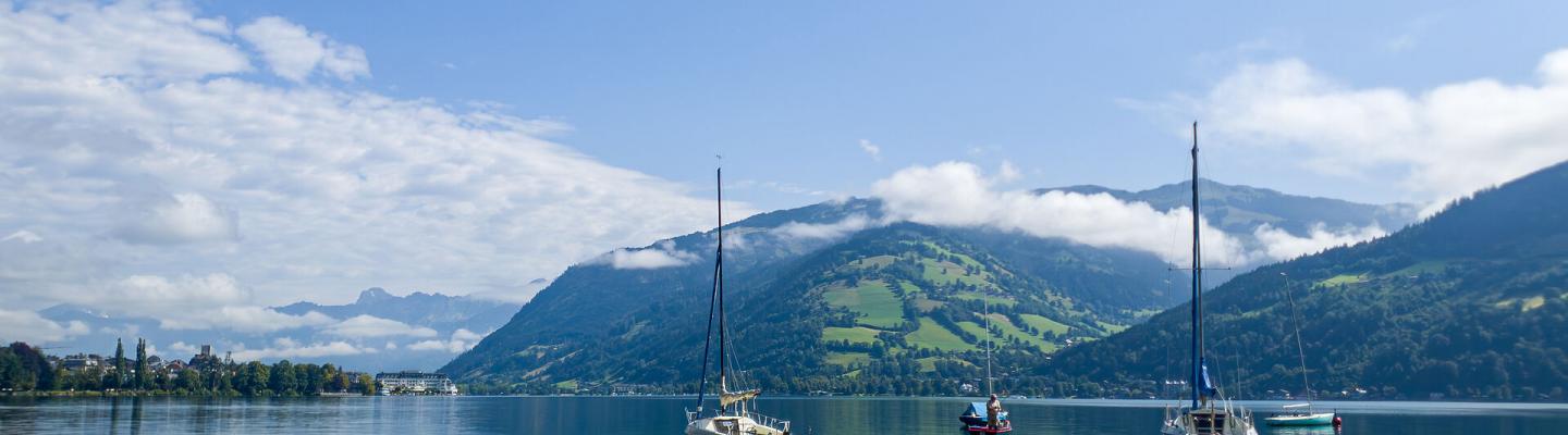 Vier Segelboote im Zeller See. Im Hintergrund sieht man die Berge.