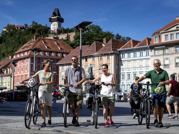 Radfahrer in Graz mit Uhrturm im Hintergrund Cyclists in Graz with clock tower in the background