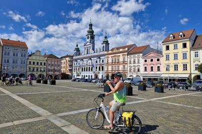 Hauptplatz von Budweis mit Radfahrer im Vordergrund und Rathaus mit Uhrturm.