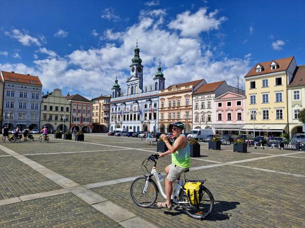 Hauptplatz von Budweis mit Radfahrer im Vordergrund und Rathaus mit Uhrturm.