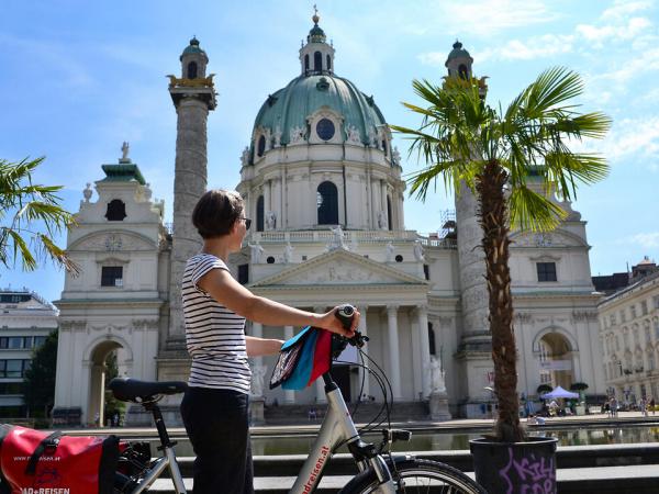 Radfahrerin vor der Karlkirche Wien